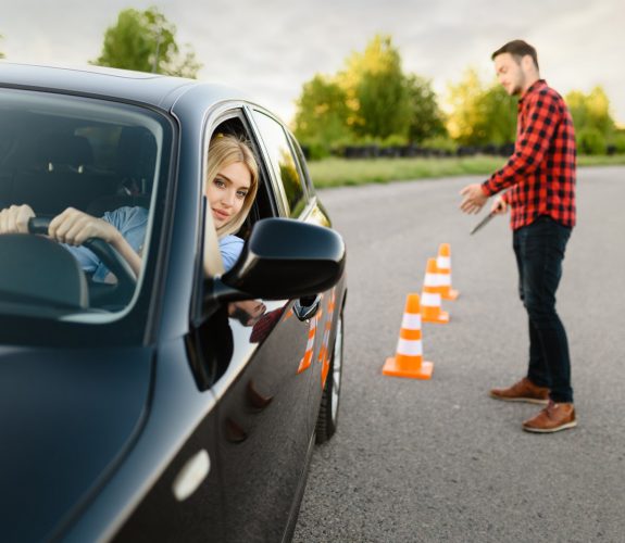 Instructor is happy with the driving of his female student between cones, lesson in driving school. Man teaching lady. Driver's license education